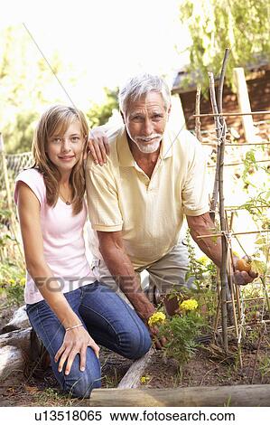 Stock Photography - Teenage Granddaughter And Grandfather Relaxing In Garden. Fotosearch
