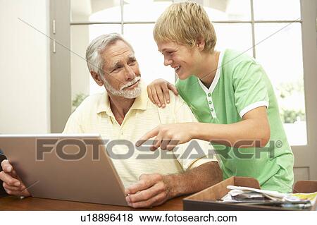 Teenage Grandson Helping Grandfather To Use Laptop At Home View Large Photo Image Stock Photo - Teenage Grandson Helping Grandfather To Use Laptop At Home. Fotosearch