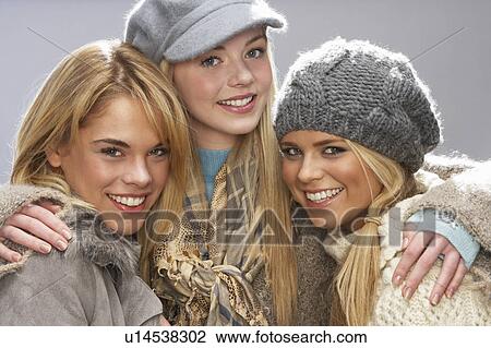 Stock Image - Three Fashionable Teenage Girls Wearing Cap And Knitwear In Studio. Fotosearch