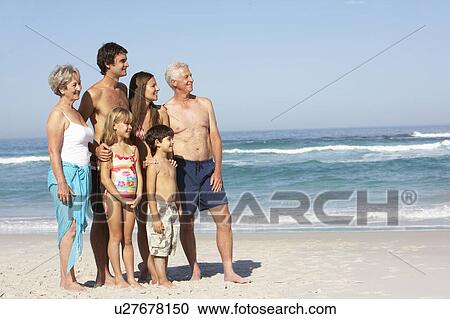 Stock Image - Three Generation Family On Holiday Walking Along Beach. Fotosearch
