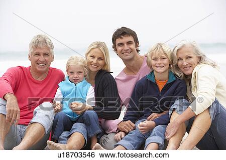 Stock Photograph - Three Generation Family Sitting On Winter Beach Together. Fotosearch