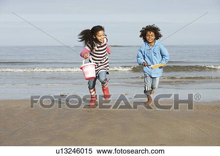 Stock Photography - Two Children Playing By Sea On Winter Beach. Fotosearch