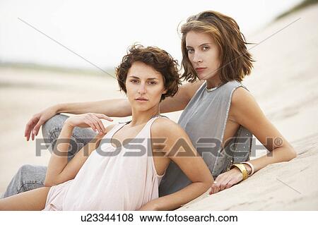 Two Fashionably Dressed Attractive Young Women Laying Amongst Sand Dunes View Large Photo Image Stock Photo - Two Fashionably Dressed Attractive Young Women Laying Amongst Sand Dunes. Fotosearch