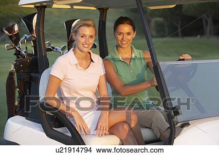 Two Female Golfers Riding In Golf Buggy On Golf Course View Large Photo Image Picture - Two Female Golfers Riding In Golf Buggy On Golf Course. Fotosearch