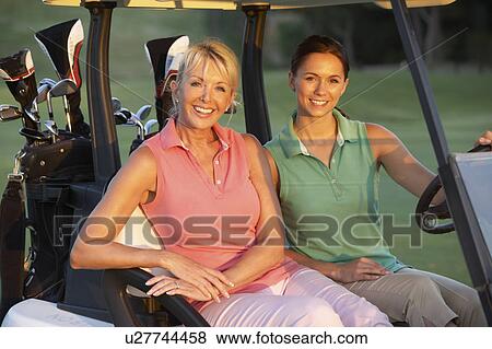 Two Female Golfers Riding In Golf Buggy On Golf Course View Large Photo Image Stock Photo - Two Female Golfers Riding In Golf Buggy On Golf Course. Fotosearch