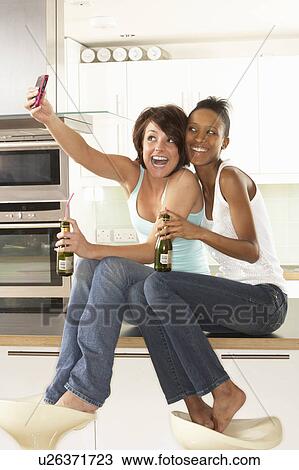 Two Girlfriends Taking Photo With Digital Camera In Modern Kitchen View Large Photo Image Stock Image - Two Girlfriends Taking Photo With Digital Camera In Modern Kitchen. Fotosearch