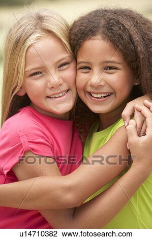 Stock Image - Two Girls In Park Giving Each Other Hug. Fotosearch