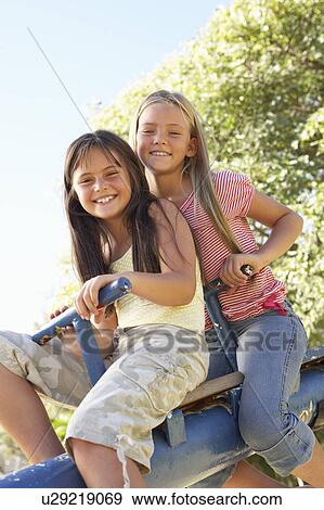 Two Girls Riding On See Saw In Playground View Large Photo Image Stock Photo - Two Girls Riding On See Saw In Playground. Fotosearch