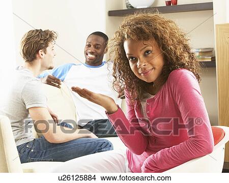 Two Male Friends Chatting Together With Bored Looking Female Partner At Home View Large Photo Image Picture - Two Male Friends Chatting Together With Bored Looking Female Partner At Home. Fotosearch
