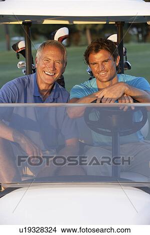 Two Male Golfers Riding In Golf Buggy On Golf Course View Large Photo Image Picture - Two Male Golfers Riding In Golf Buggy On Golf Course. Fotosearch