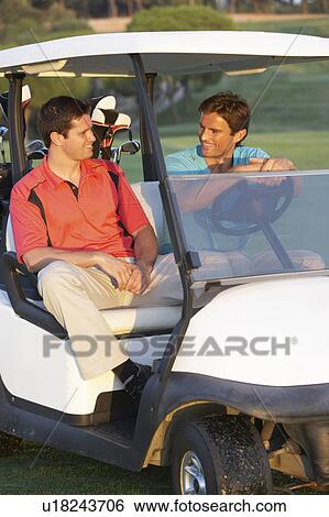 Stock Photograph - Two Male Golfers Riding In Golf Buggy On Golf Course. Fotosearch