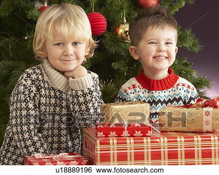 Two Young Boys With Presents In Front Of Christmas Tree View Large Photo Image Stock Photograph - Two Young Boys With Presents In Front Of Christmas Tree. Fotosearch