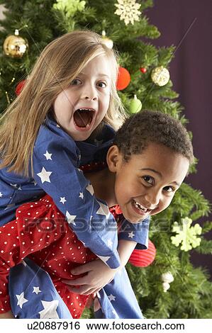 Two Young Children Having Fun In Front Of Christmas Tree View Large Photo Image Stock Photograph - Two Young Children Having Fun In Front Of Christmas Tree. Fotosearch