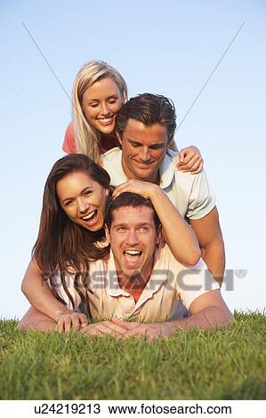 Two, young couples posing on a field View Large Photo Image Stock Image - Two, young couples posing on a field. Fotosearch