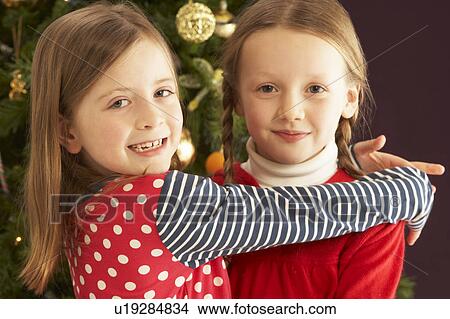 Two Young Girls Hugging In Front Of Christmas Tree View Large Photo Image Picture - Two Young Girls Hugging In Front Of Christmas Tree. Fotosearch