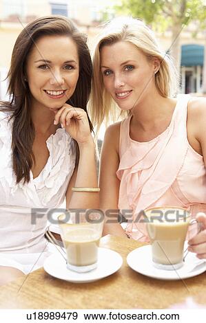 Stock Photo - Two Young Women Enjoying Cup Of Coffee In Café. Fotosearch