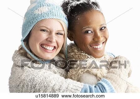 Stock Photo - Two Young Women Wearing Warm Winter Clothes Holding Snowball In Studio. Fotosearch