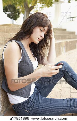 Unhappy Female Teenage Student Sitting Outside On College Steps Using Mobile Phone View Large Photo Image Stock Photograph - Unhappy Female Teenage Student Sitting Outside On College Steps Using Mobile Phone. Fotosearch