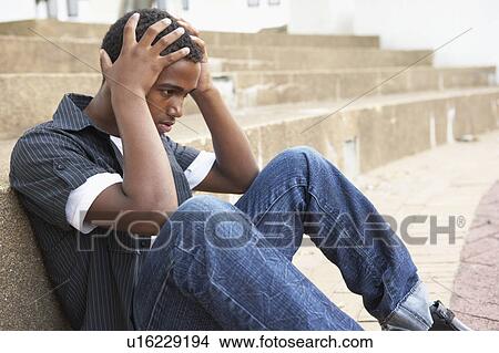 Picture - Unhappy Male Teenage Student Sitting Outside On College Steps. Fotosearch