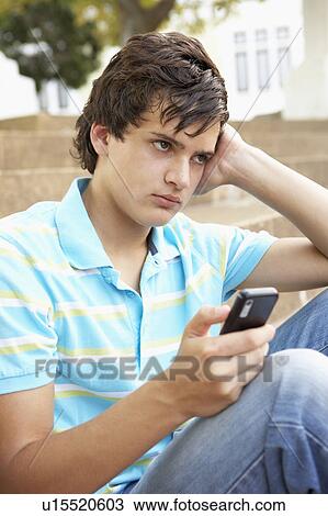 Unhappy Male Teenage Student Sitting Outside On College Steps Using Mobile Phone View Large Photo Image Stock Image - Unhappy Male Teenage Student Sitting Outside On College Steps Using Mobile Phone. Fotosearch