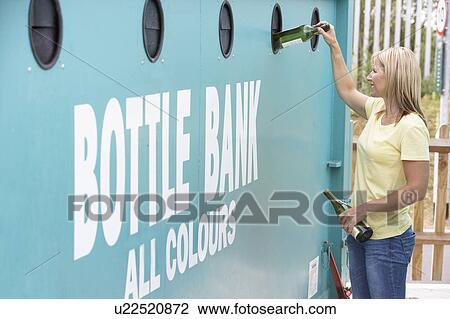 Stock Image - Woman At Recycling Centre Disposing Of Glass At Bottle Bank. Fotosearch