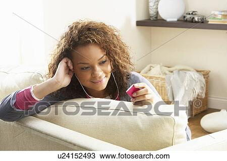 Woman Listening To MP3 Player On Headphones Relaxing Sitting On Rug At Home View Large Photo Image Stock Image - Woman Listening To MP3 Player On Headphones Relaxing Sitting On Rug At Home . Fotosearch