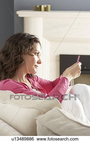Woman Listening To MP3 Player On Headphones Relaxing Sitting On Rug At Home View Large Photo Image Stock Photograph - Woman Listening To MP3 Player On Headphones Relaxing Sitting On Rug At Home . Fotosearch
