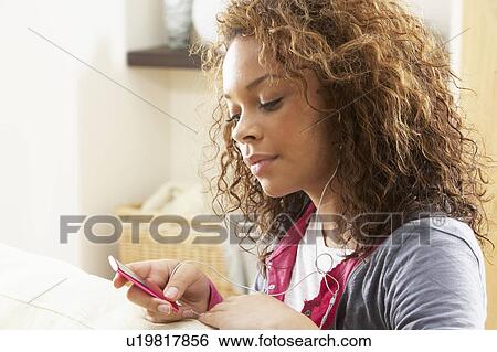 Woman Listening To MP3 Player On Headphones Relaxing Sitting On Rug At Home View Large Photo Image Stock Photograph - Woman Listening To MP3 Player On Headphones Relaxing Sitting On Rug At Home . Fotosearch