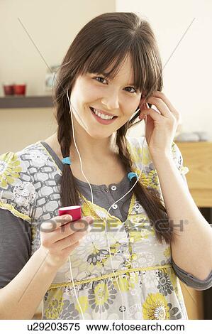 Stock Photography - Woman Listening To MP3 Player On Headphones Relaxing Sitting On Rug At Home . Fotosearch