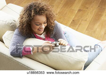 Woman Looking At Pictures On Digital Camera Relaxing Sitting On Sofa At Home View Large Photo Image Stock Image - Woman Looking At Pictures On Digital Camera Relaxing Sitting On Sofa At Home. Fotosearch