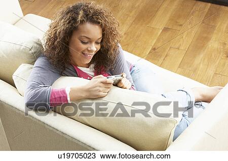 Woman Looking At Pictures On Digital Camera Relaxing Sitting On Sofa At Home View Large Photo Image Stock Image - Woman Looking At Pictures On Digital Camera Relaxing Sitting On Sofa At Home. Fotosearch