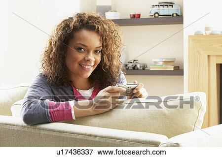 Woman Looking At Pictures On Digital Camera Relaxing Sitting On Sofa At Home View Large Photo Image Stock Photo - Woman Looking At Pictures On Digital Camera Relaxing Sitting On Sofa At Home . Fotosearch