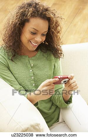 Woman Looking At Pictures On Digital Camera Relaxing Sitting On Sofa At Home View Large Photo Image Stock Photo - Woman Looking At Pictures On Digital Camera Relaxing Sitting On Sofa At Home. Fotosearch