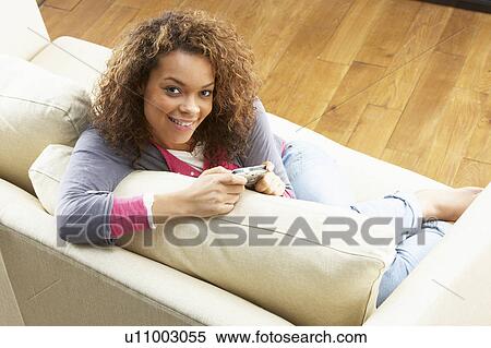Stock Photography - Woman Looking At Pictures On Digital Camera Relaxing Sitting On Sofa At Home . Fotosearch