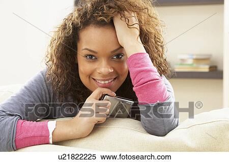 Stock Photography - Woman Looking At Pictures On Digital Camera Relaxing Sitting On Sofa At Home . Fotosearch