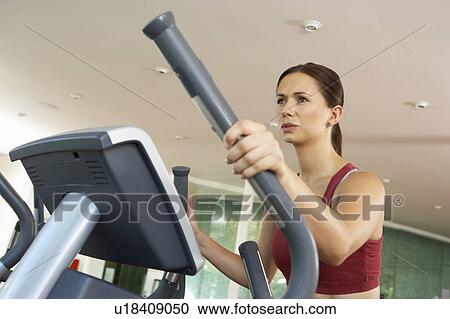 Stock Image - Woman On Cross Trainer Machine In Gym. Fotosearch