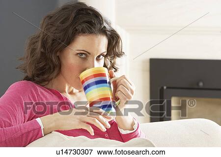 Stock Photo - Woman Relaxing On Sofa At Home Drinking Cup Of Coffee. Fotosearch