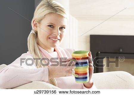 Stock Photograph - Woman Relaxing On Sofa At Home Drinking Cup Of Coffee. Fotosearch