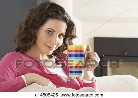 Stock Photography - Woman Relaxing On Sofa At Home Drinking Cup Of Coffee. Fotosearch