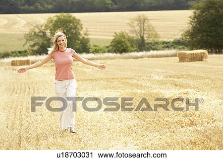 Stock Image - Woman Running Through Summer Harvested Field. Fotosearch