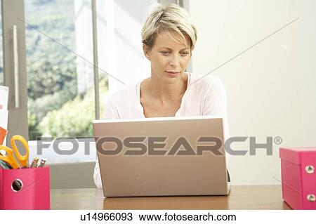 Stock Image - Woman Using Laptop At Home. Fotosearch