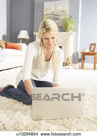 Picture - Woman Using Laptop Relaxing Sitting On Rug At Home. Fotosearch
