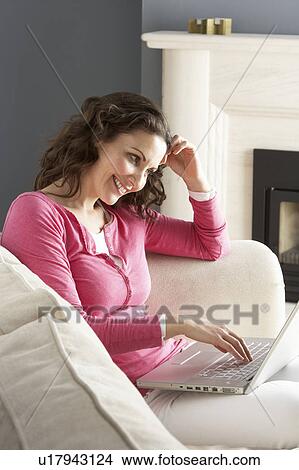 Picture - Woman Using Laptop Relaxing Sitting On Sofa At Home . Fotosearch