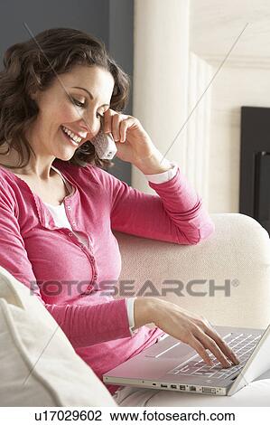 Woman Using Laptop Relaxing Sitting On Sofa At Home Talking On Phone View Large Photo Image Stock Image - Woman Using Laptop Relaxing Sitting On Sofa At Home Talking On Phone. Fotosearch