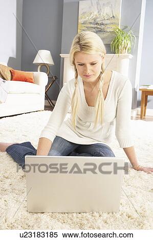 Stock Photography - Woman Using Laptop Relaxing Sitting On Rug At Home. Fotosearch