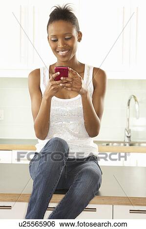 Woman Using Mobile Phone Sitting In Modern Kitchen View Large Photo Image Stock Photograph - Woman Using Mobile Phone Sitting In Modern Kitchen . Fotosearch