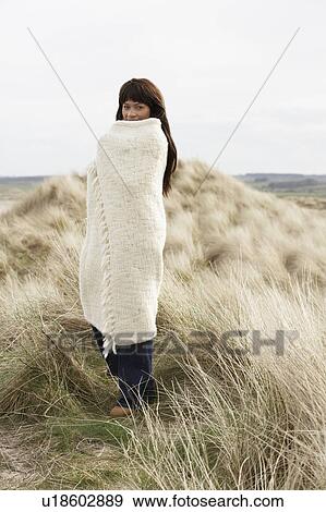 Stock Photo - Woman Wrapped In Blanket Amongst Dunes On Winter Beach. Fotosearch