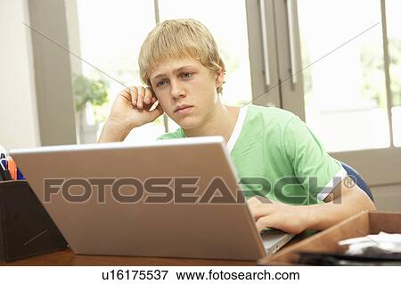 Stock Photo - Worried Looking Teenage Boy Using Laptop At Home. Fotosearch