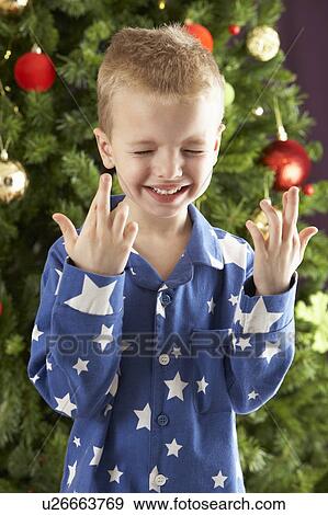 Stock Photo - Young Boy Crossing Fingers In Front Of Christmas Tree. Fotosearch
