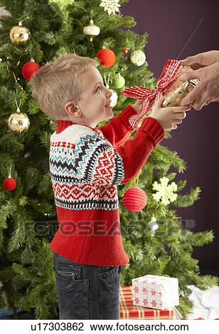 Young Boy Holding Christmas Present In Front Of Christmas Tree View Large Photo Image Stock Image - Young Boy Holding Christmas Present In Front Of Christmas Tree. Fotosearch